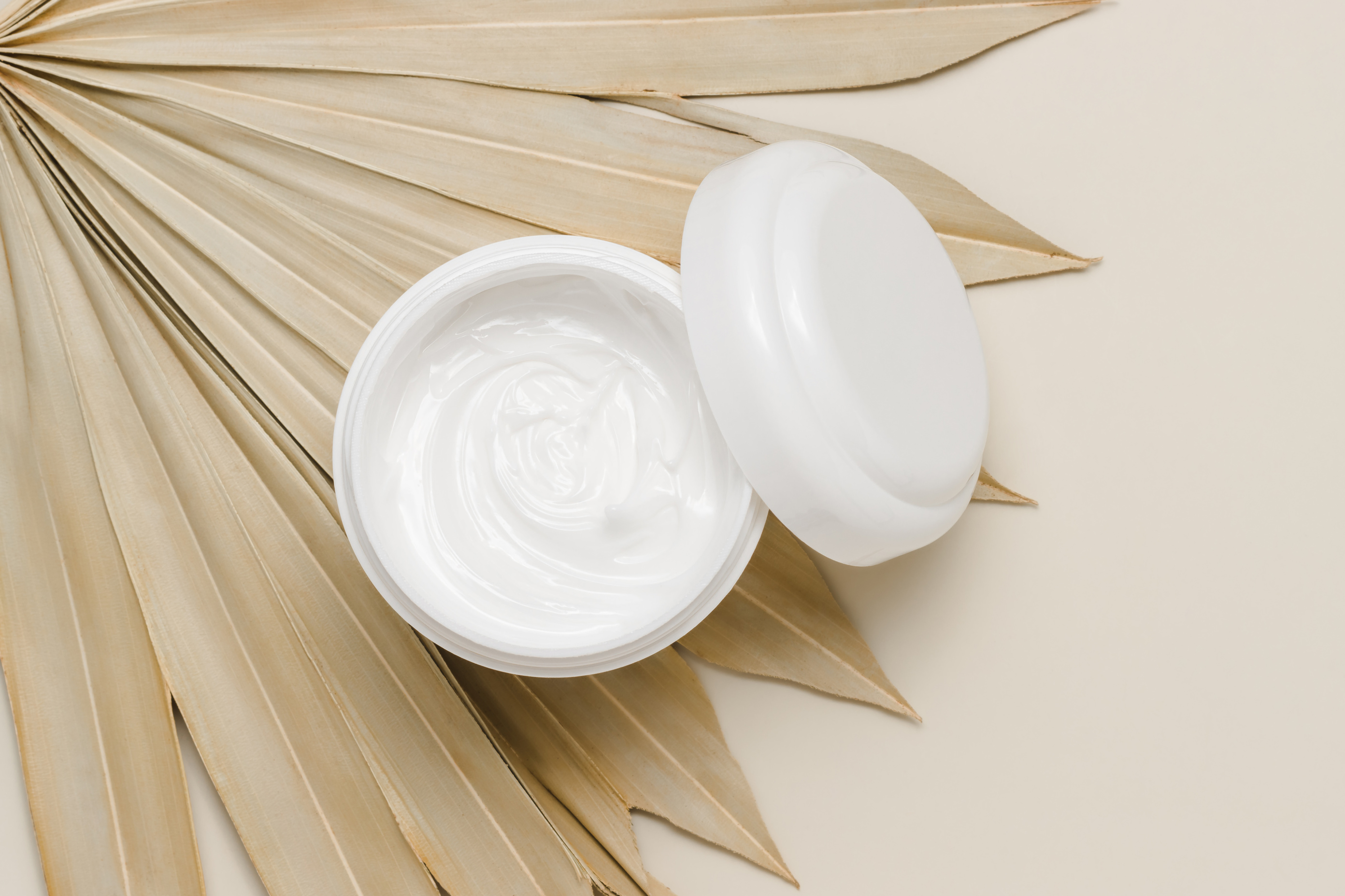 Natural moisturizing cream close up on palm leaf